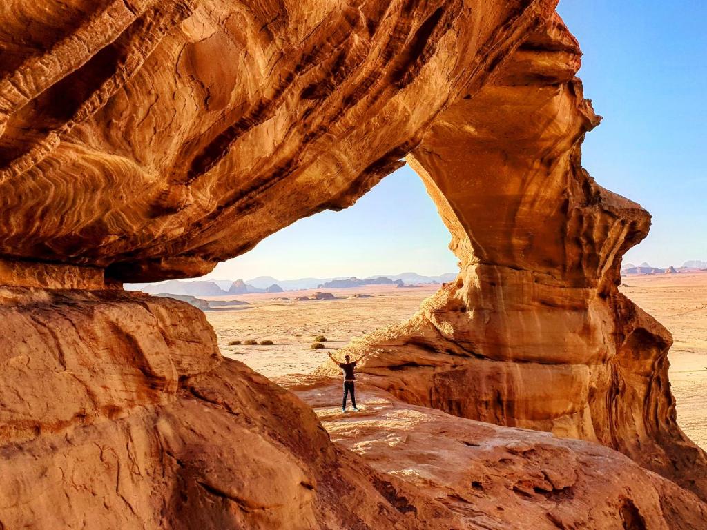a man standing in front of an arch in the desert at Wadi Rum Fire Camp in Wadi Rum