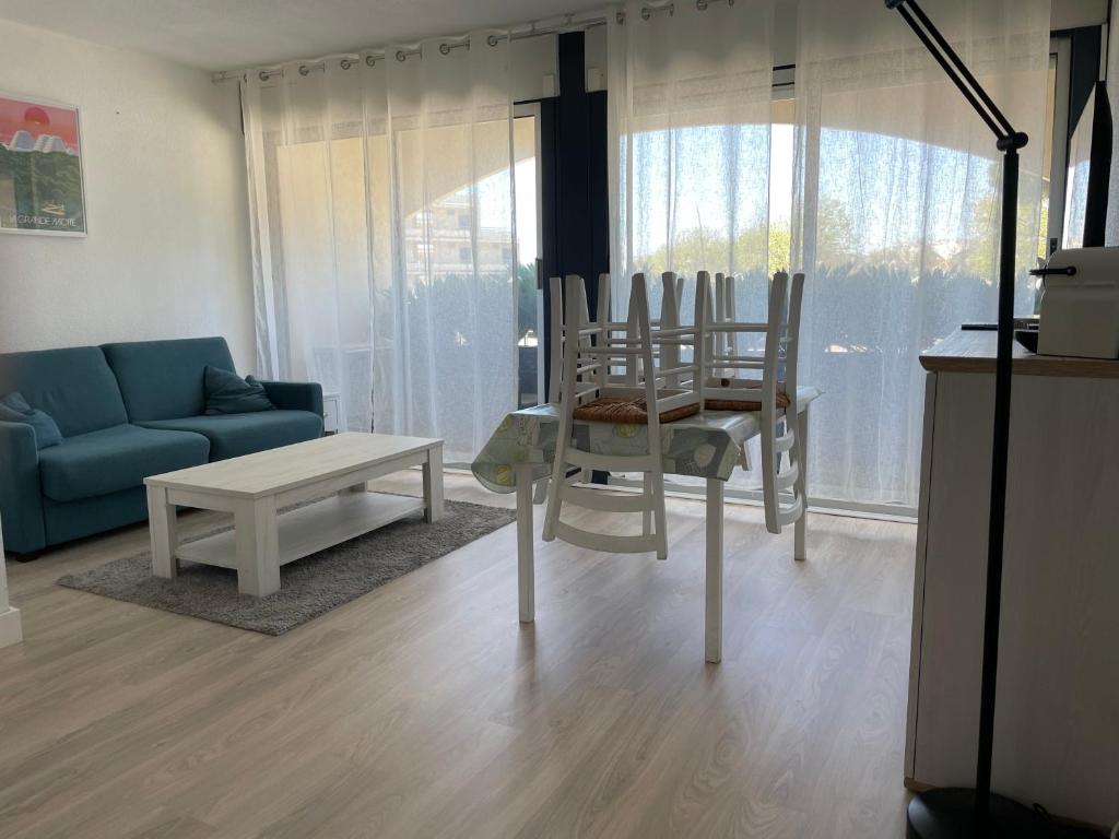 a living room with a blue couch and chairs at LES TERRASSES DE LA MER - PARKING - WIFI - CLIM - accès privé plage - point zéro in La Grande-Motte
