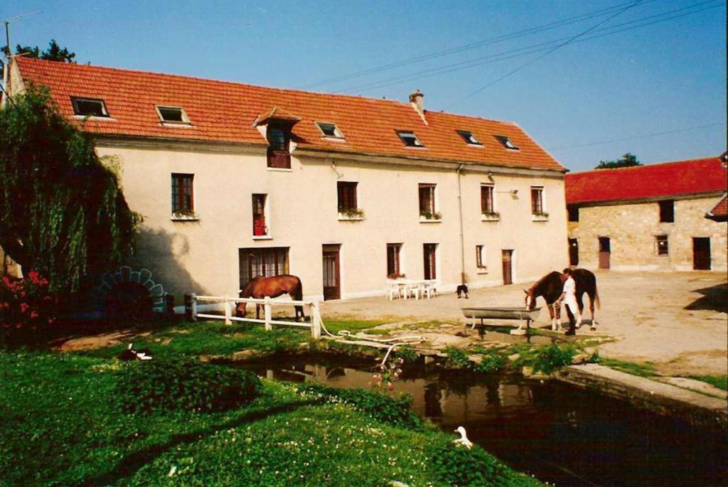 ein Gebäude mit zwei Pferden, die Wasser aus einem Teich trinken in der Unterkunft Maison de 7 chambres avec jardin clos et wifi a Viarmes in Viarmes