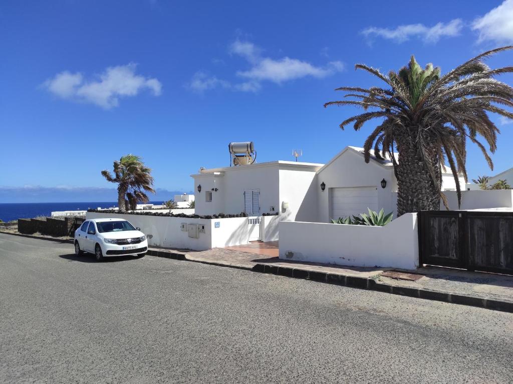 a white car parked on a street next to a house at Casa de los pajaritos. in Charco del Palo