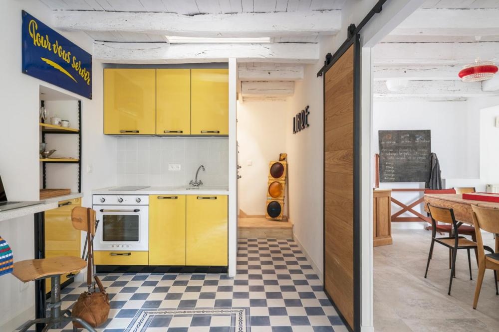 a kitchen with yellow cabinets and a checkered floor at Maison atypique au sein du joli village de Trentemoult in Rezé