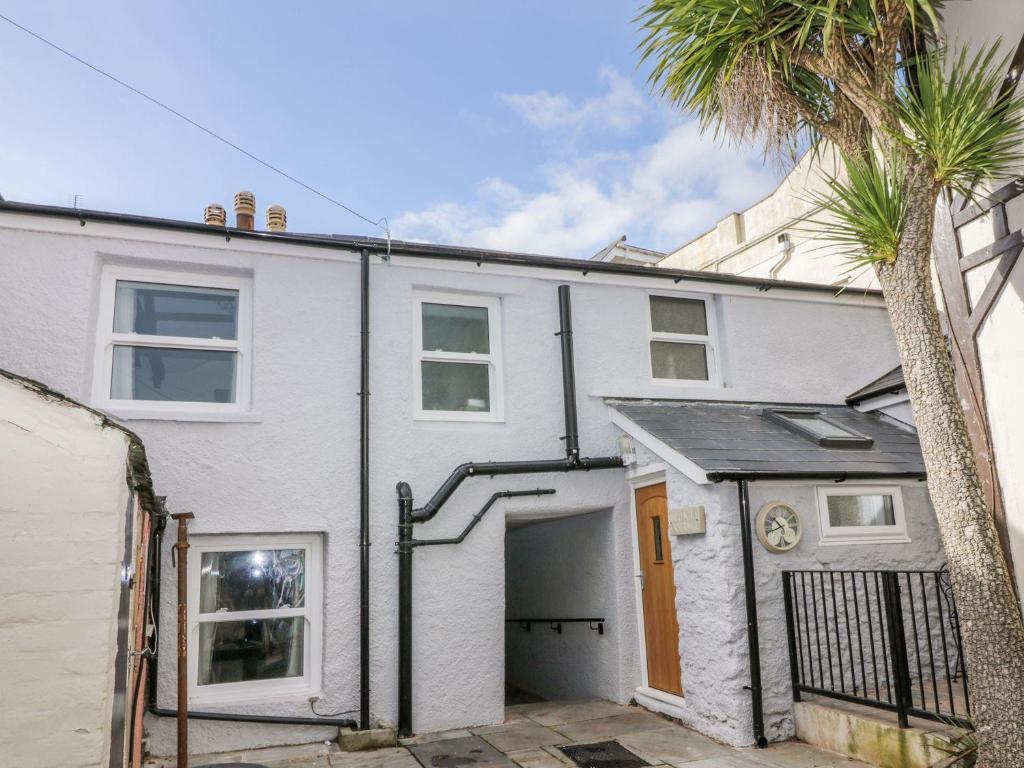 a white house with a garage and a palm tree at Hocking Cottage in Torquay