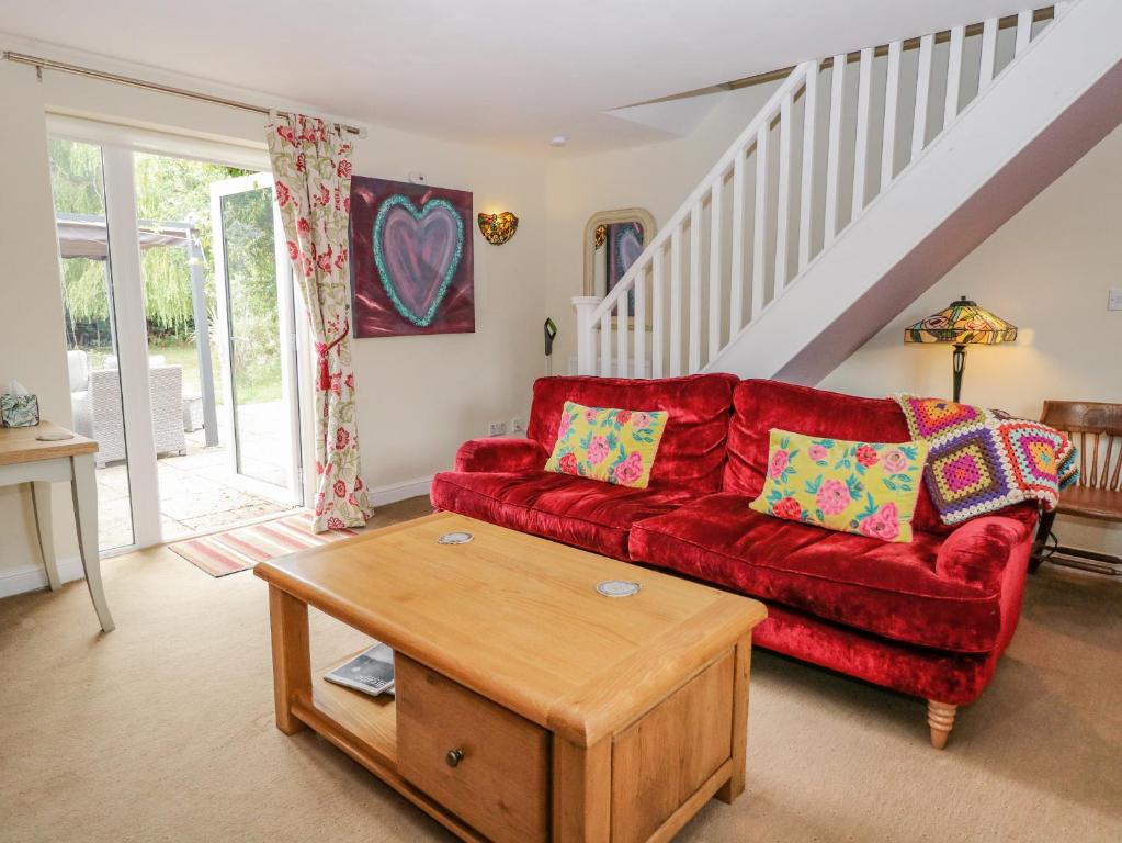 a living room with a red couch and a table at Willow Cottage in Norwich