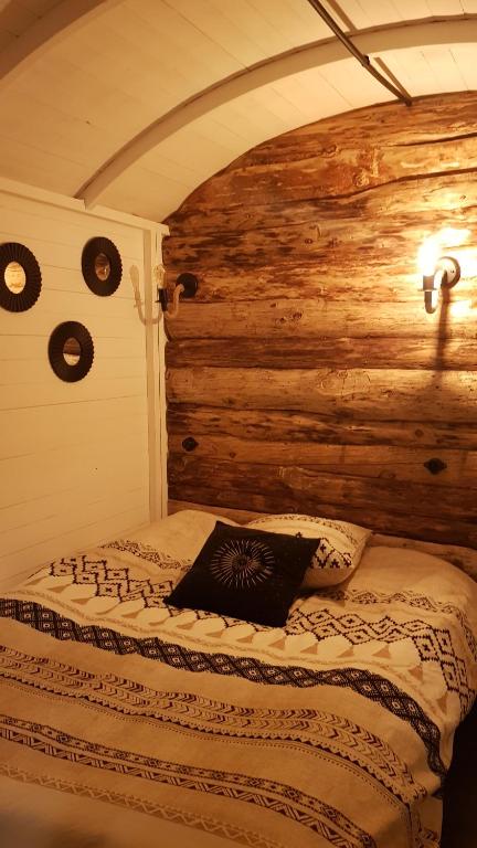 a bed in a room with a wooden wall at Amarok in Muhlbach-sur-Munster