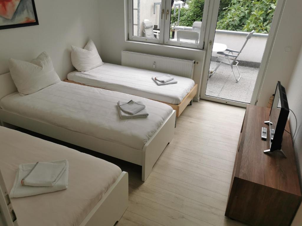 a small room with two beds and a balcony at Ferdimesse Apartments in Cologne