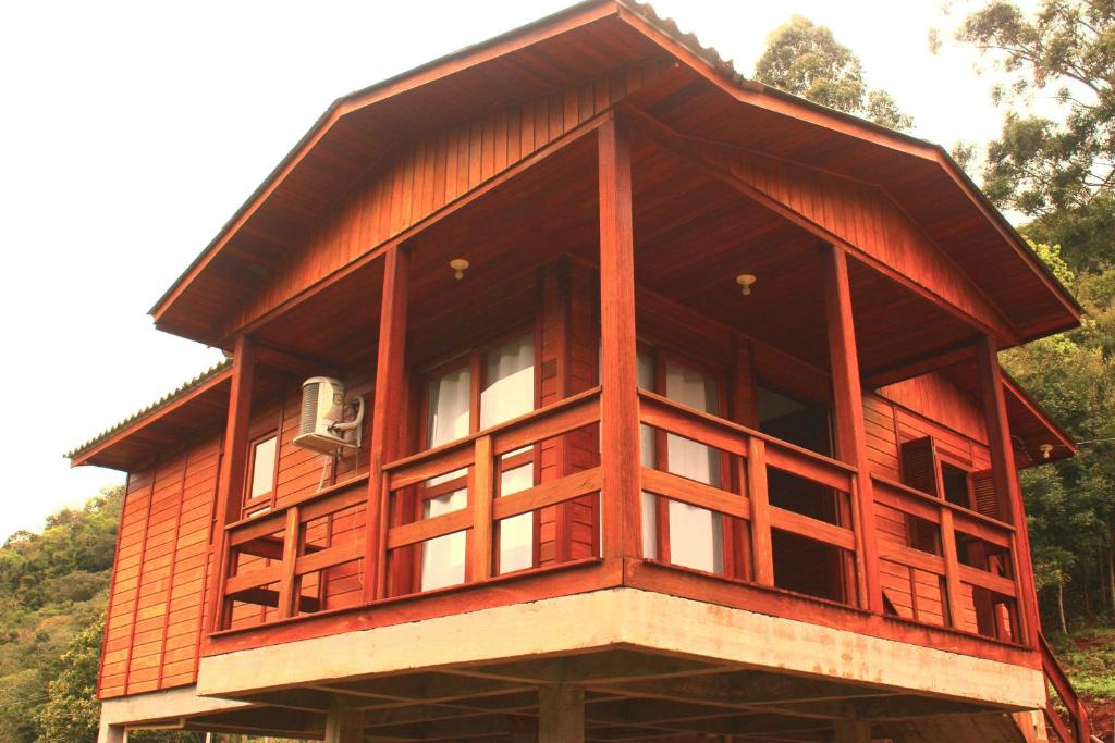 een houten huis met een balkon erboven bij Cabana das Montanhas in Caxias do Sul