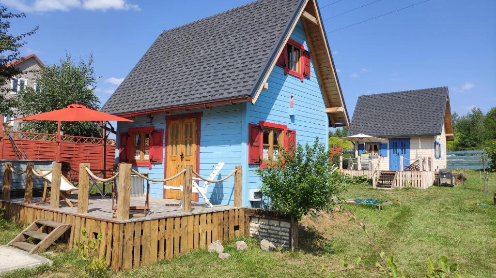 a blue house with a porch and a deck at Skotopaska & Bukolika in Idzbark