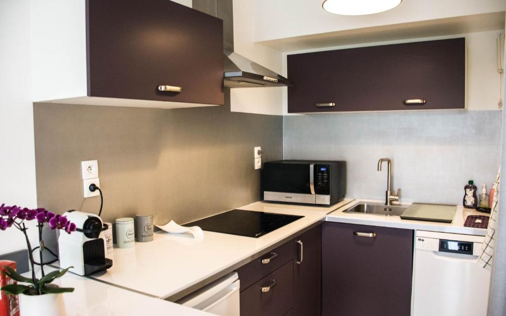 a kitchen with a sink and a microwave at Sweet apartment in front of Disneyland's castel in Montévrain