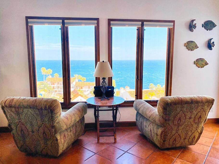 a living room with two chairs and a table with a lamp at Sunrise Bliss Villa in Avalon