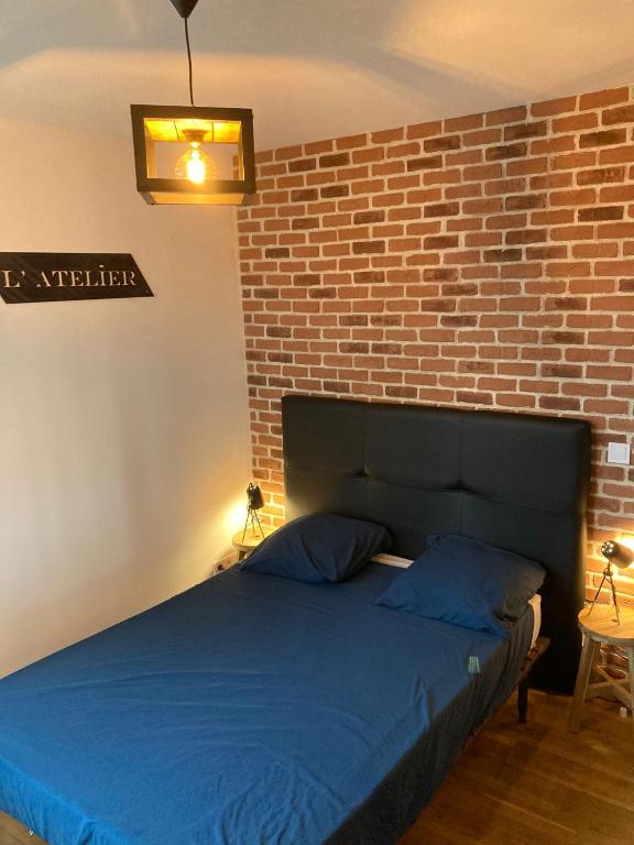 - une chambre avec un lit bleu et un mur en briques dans l'établissement Villa Sagrada l'Atelier ****, à Toulouse