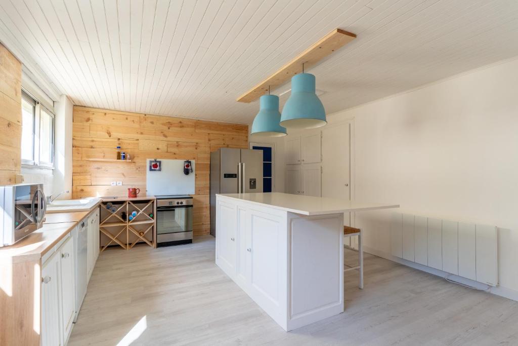 a kitchen with white cabinets and wooden walls at Maison Mimizan plage in Mimizan