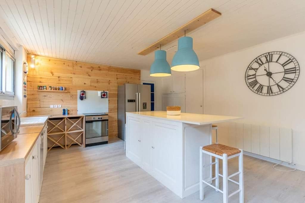 a kitchen with a counter and a clock on the wall at Maison Mimizan plage in Mimizan