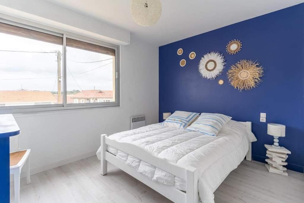 a blue bedroom with a white bed and a window at Maison Mimizan plage in Mimizan