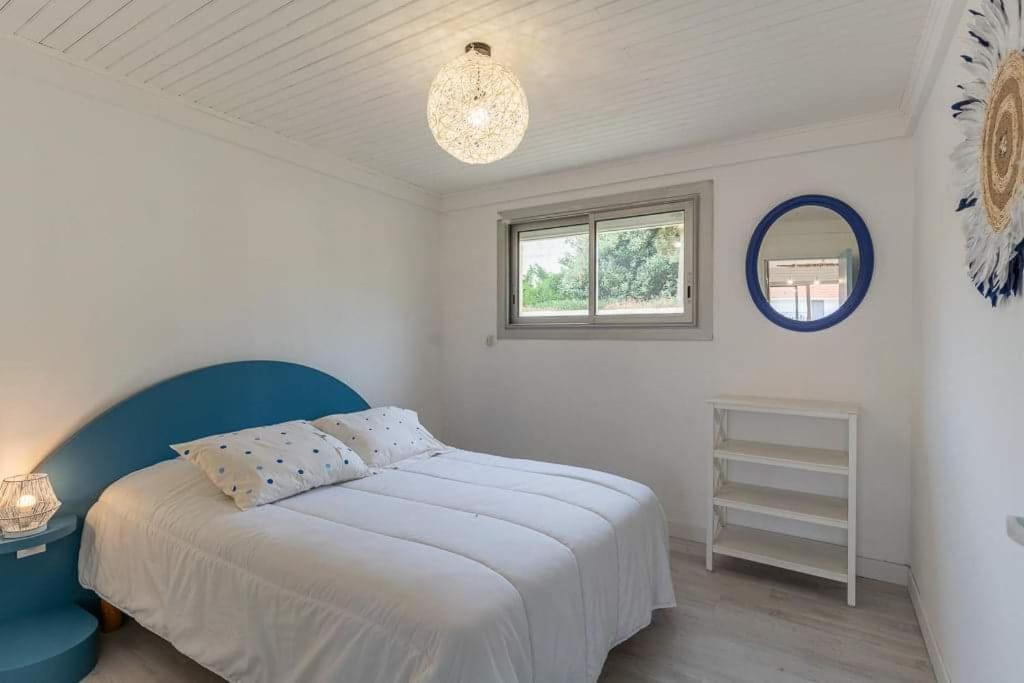 a white bedroom with a bed and a window at Maison Mimizan plage in Mimizan