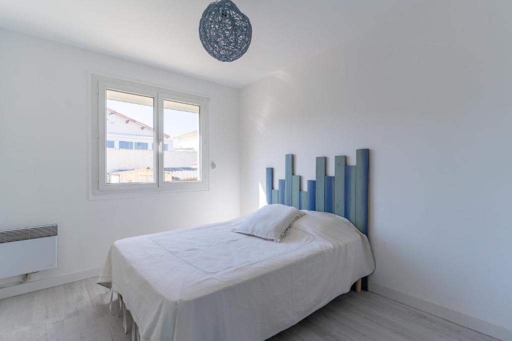 a white bedroom with a bed and a window at Maison Mimizan plage in Mimizan