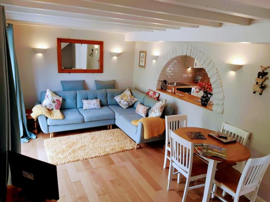 a living room with a blue couch and a table at Hidden gem on the edge of the Cotswolds in Charfield
