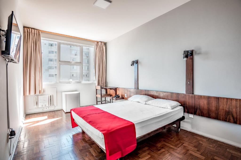 Un dormitorio con una cama con una manta roja. en Cannes Palace Hotel en Vitória