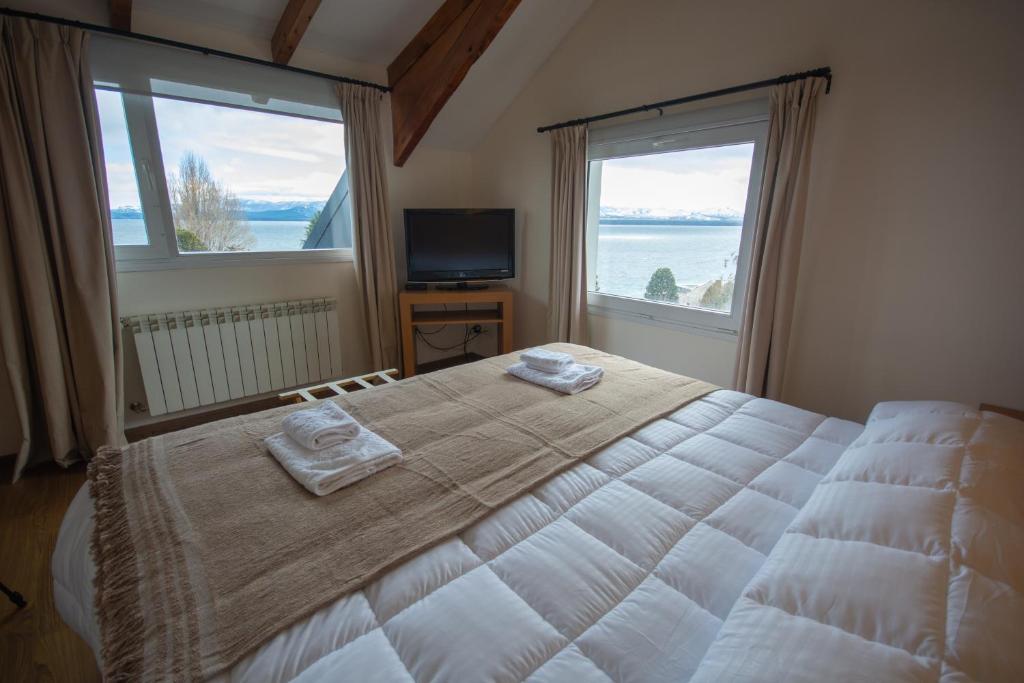 um quarto com uma cama grande e 2 janelas em NBH Nativo Boutique Hotel em San Carlos de Bariloche