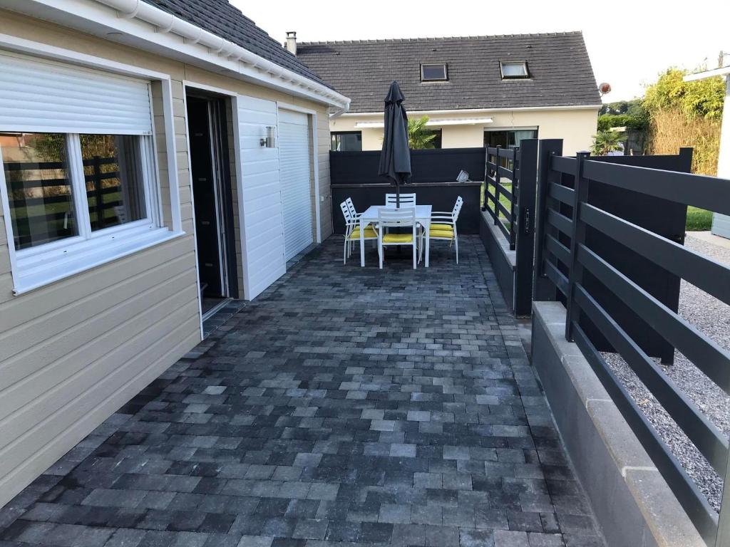 a patio with a table and chairs on a house at Gîte spa sauna piscine in Aubin-Saint-Vaast