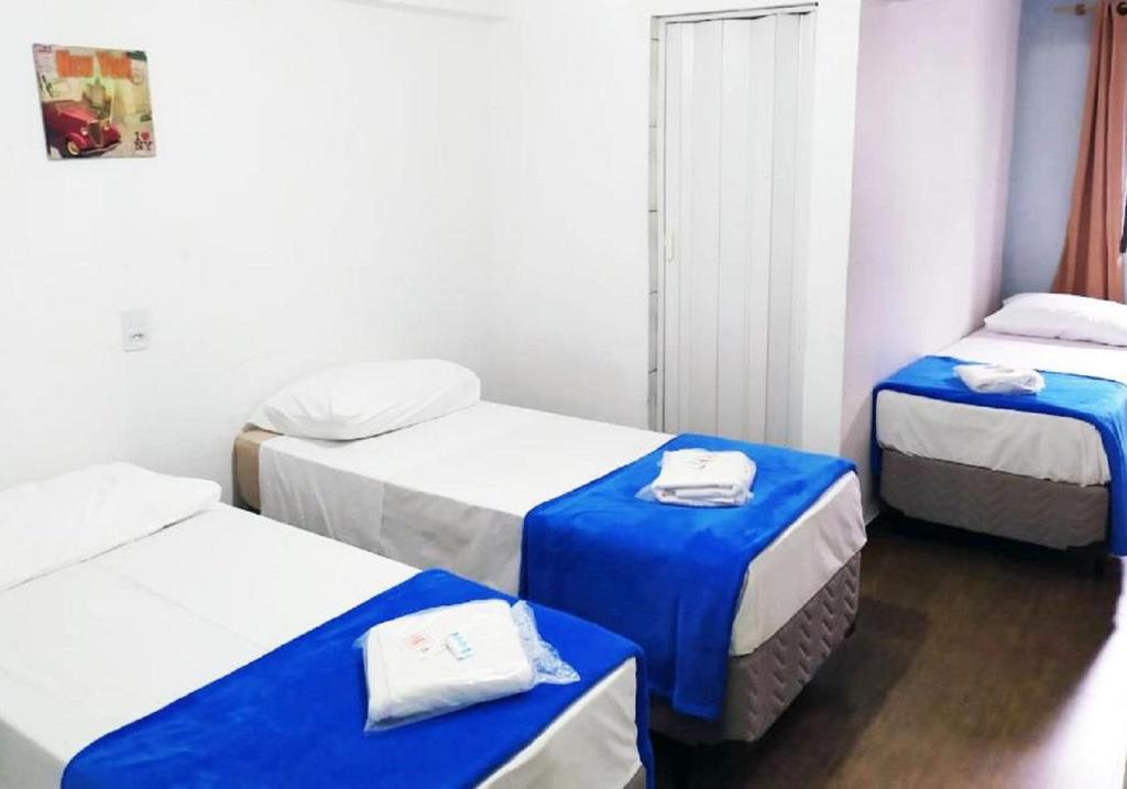 Habitación con 3 camas con sábanas azules y blancas. en Hotel Digital Ponte Aerea - Aeroporto de Congonhas, en São Paulo