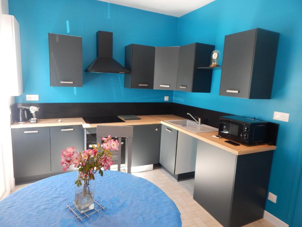 una cocina con un jarrón de flores sobre una mesa en SAINT MALO bel appartement plain pied 300 m gare prés plage du sillon Intramuros a pied, en Saint-Malo