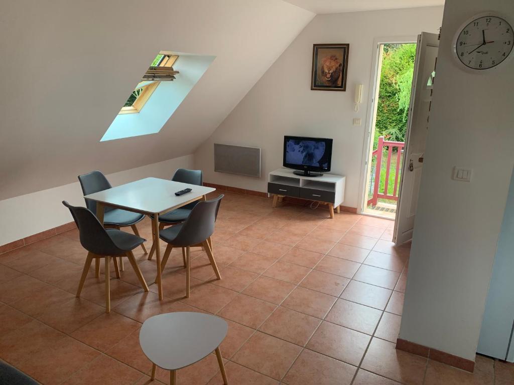 ein Wohnzimmer mit einem Tisch und Stühlen sowie einem TV in der Unterkunft Appartement situé prés des plages et du golf in Saint-Briac-sur-Mer