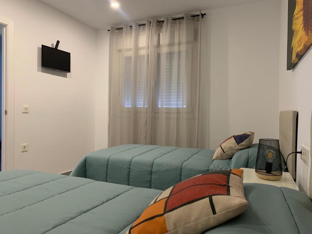 sypialnia z 2 łóżkami i telewizorem w obiekcie APARTAMENTO ENCANTO II w mieście Conil de la Frontera