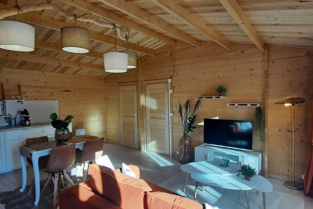 ein Wohnzimmer mit einem Sofa, einem Tisch und einem TV in der Unterkunft Chalet 1 chambre 2-4 personnes in Villainville
