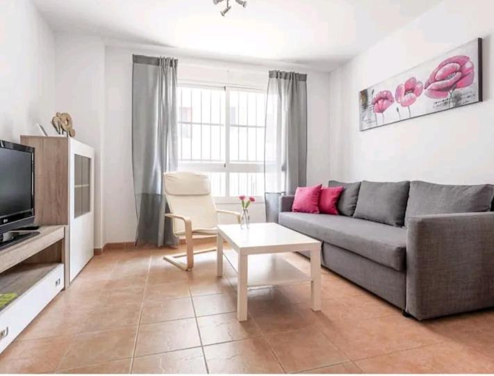 uma sala de estar com um sofá e uma mesa em Apartamento con patio y piscina cerca de Sevilla em La Algaba