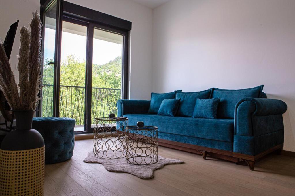 ein blaues Sofa im Wohnzimmer mit Fenster in der Unterkunft Apartment Ilija in Tivat