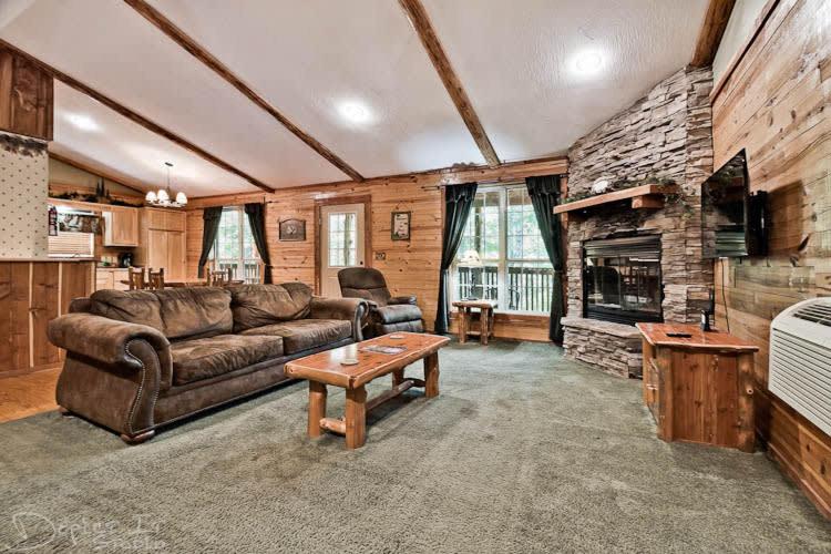 a living room with a couch and a stone fireplace at Secluded Cabin Pool WiFi smart TVs Beaver lake in Eureka Springs
