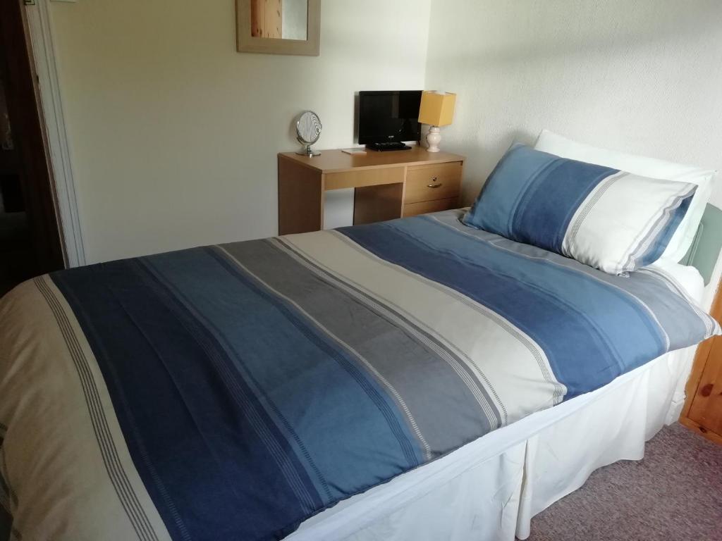 a bedroom with a bed with blue sheets and a tv at Beechlands B & B in Whitby