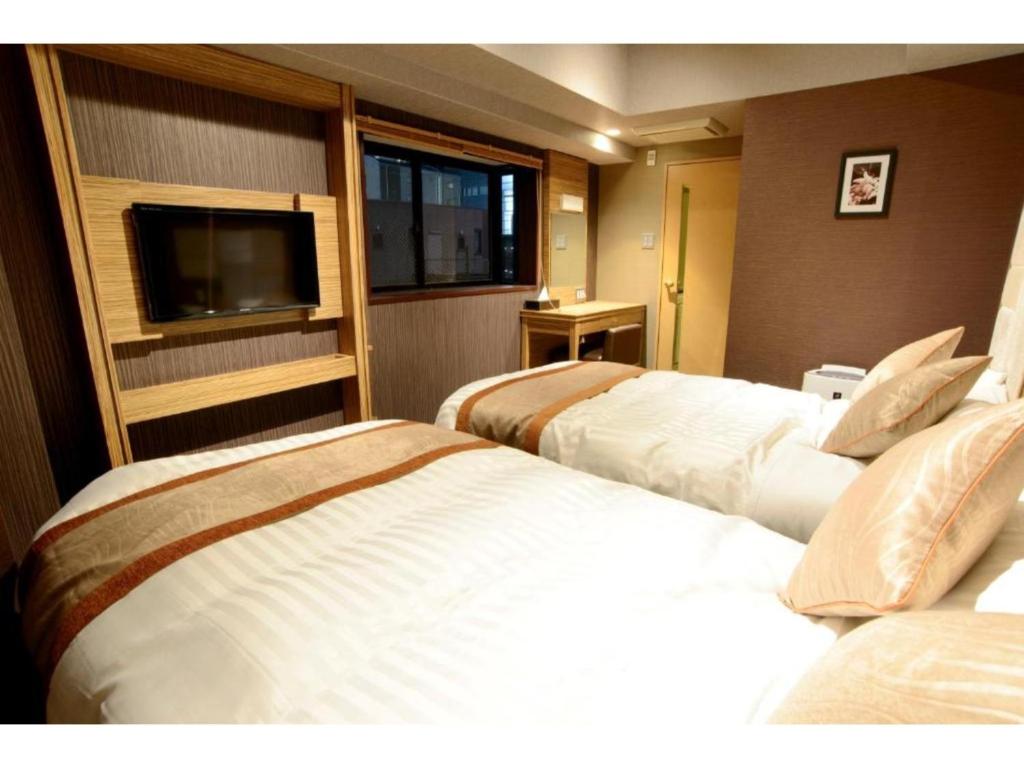 a hotel room with two beds and a flat screen tv at HOTEL RELIEF Namba Daikokuchou - Vacation STAY 33958v in Osaka