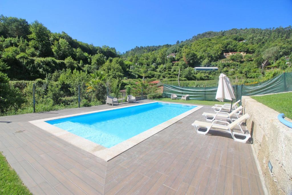 a swimming pool with two lounge chairs next to a mountain at Casa dos Henriques Gerês in Geres