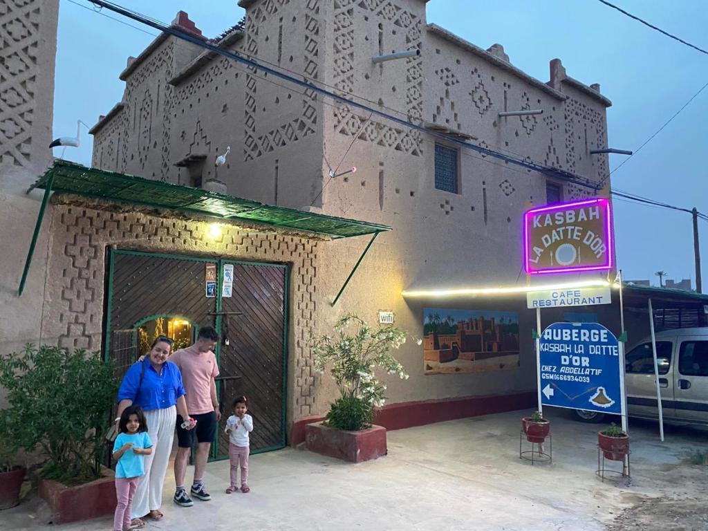 une famille se tient à l'extérieur d'un bâtiment dans l'établissement Kasbah La Datte D'or, à Skoura