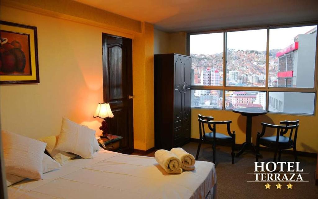 a hotel room with two beds and a table and a window at Terraza Hotel in La Paz
