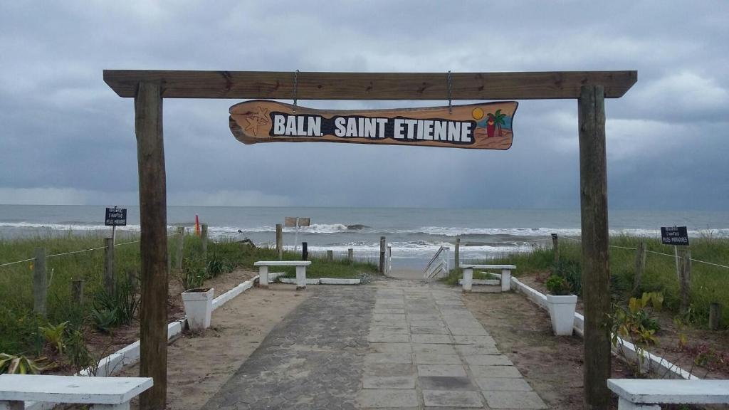 ein Schild für einen Strand mit Bänken und dem Meer in der Unterkunft Matinhos 150 metros da praia in Matinhos