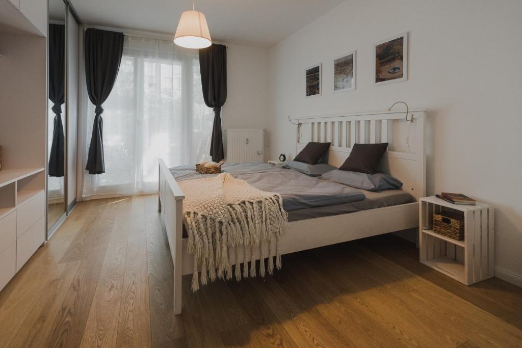 een slaapkamer met een groot bed en een houten vloer bij Quiet apartment in new city center, NIVY in Nivy