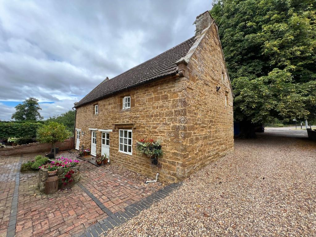 an old brick building with flowers in front of it at Braunston Manor Cottage in Braunston