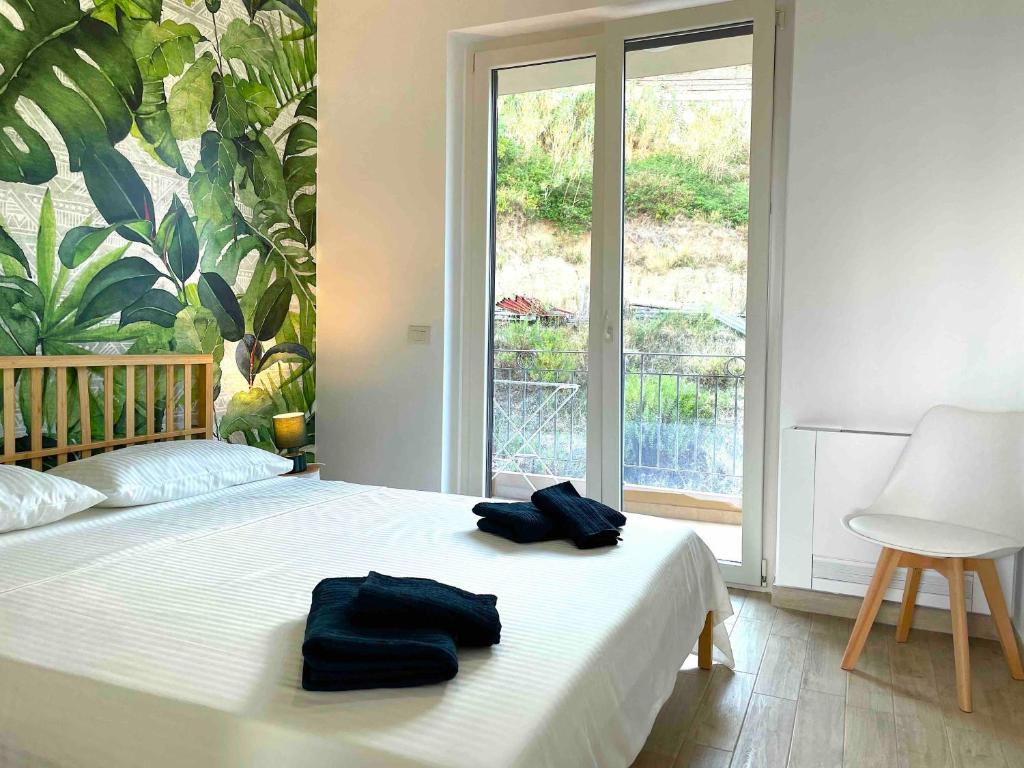 a bedroom with a bed with two black towels on it at Casa Cannoni - Delizioso Appartamento Fronte Mare vista Stretto di Messina in Messina