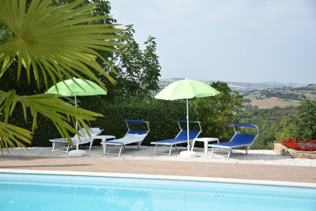 a group of chairs and umbrellas next to a pool at Casale di Maro in Monte Giberto