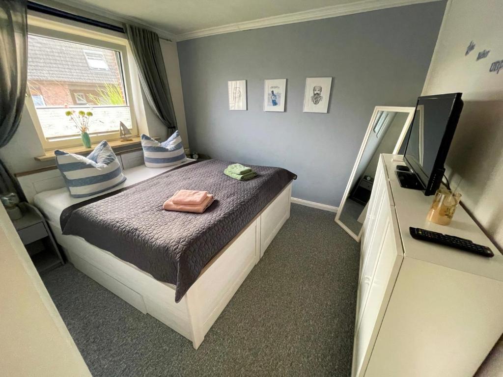 1 dormitorio con 1 cama con espejo y TV en Ferienwohnung „Deichgeflüster“ nahe der Nordsee, en Marne