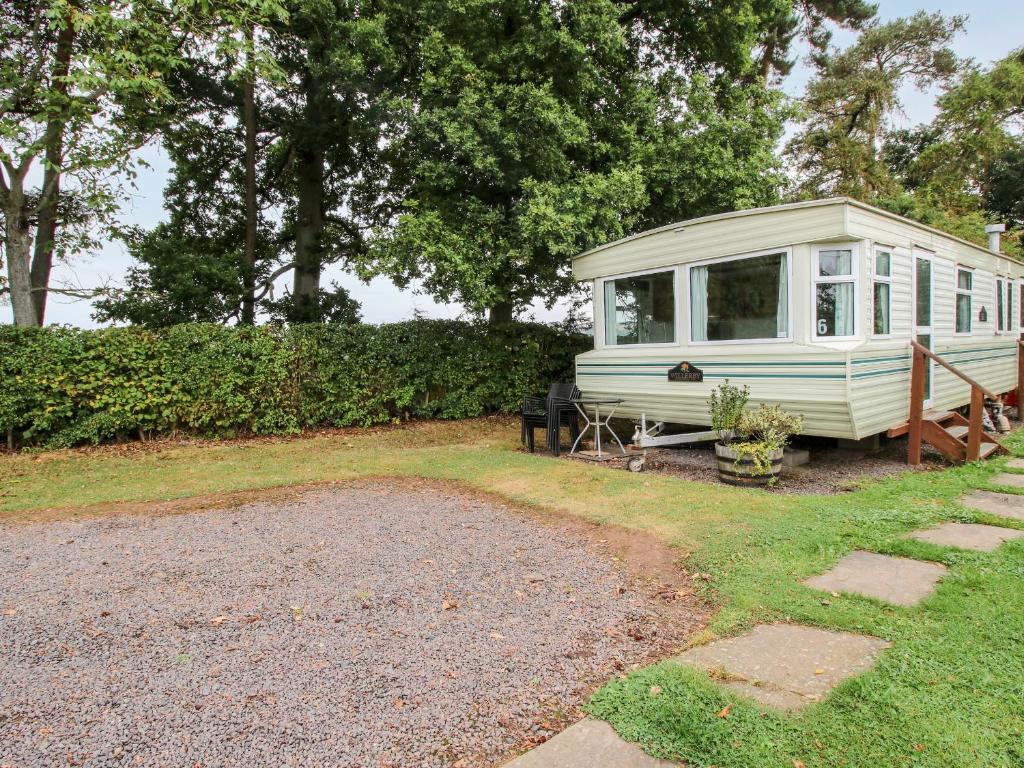 a white caravan parked in a yard next to trees at 6 Old Orchard in Much Wenlock