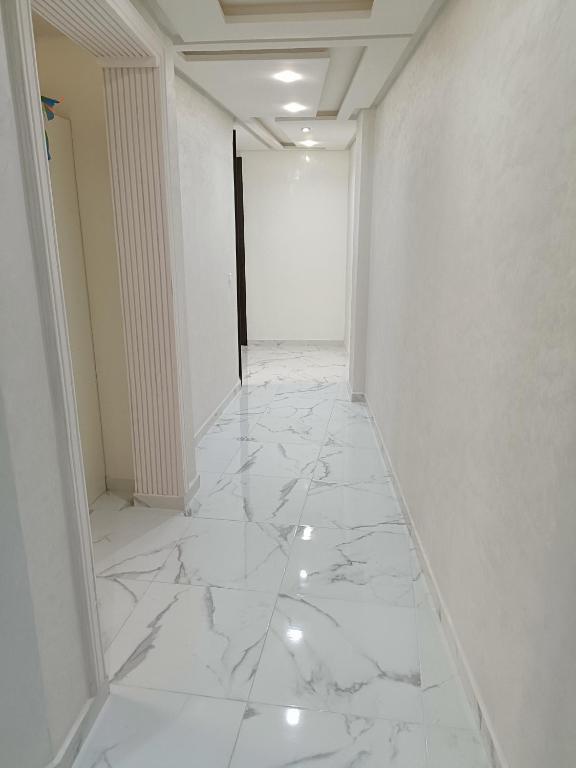 an empty hallway with white marble floors and walls at Nador hay al Matar in Nador