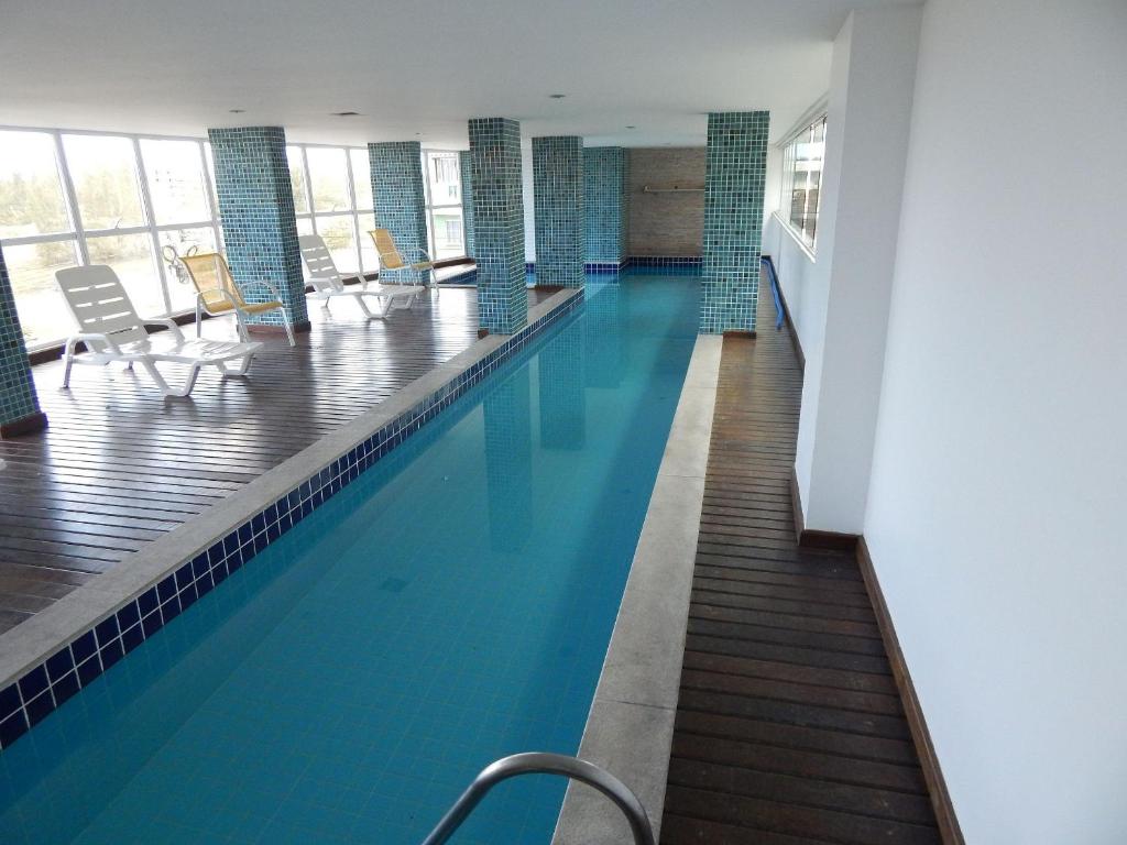 een zwembad met blauw water in een gebouw bij Condomínio Sant Martin - Alto luxo com piscina, churrasqueira e academia in Cabo Frio