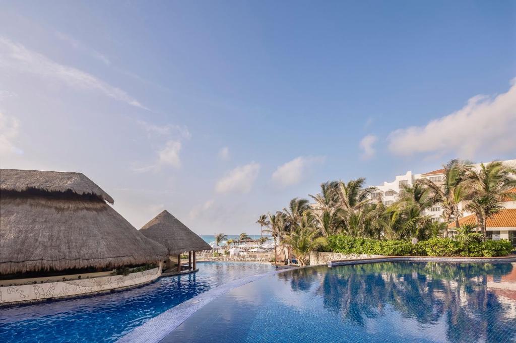 a swimming pool at a resort with palm trees at Fiesta Americana Condesa Cancun - All Inclusive in Cancún