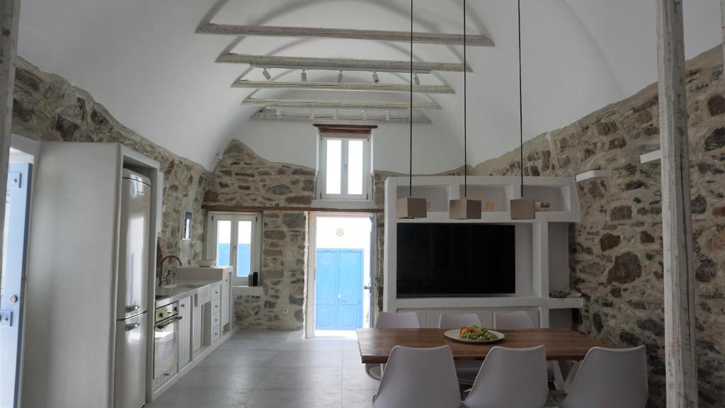 a kitchen and dining room with a table and a tv at Traditional Holiday Home in Astypalaia