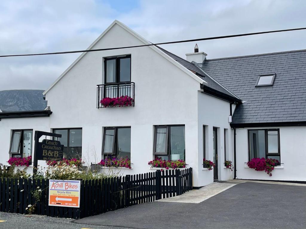 uma casa branca com caixas de flores nas janelas em Teach Cruachan Bed and Breakfast em Dooagh