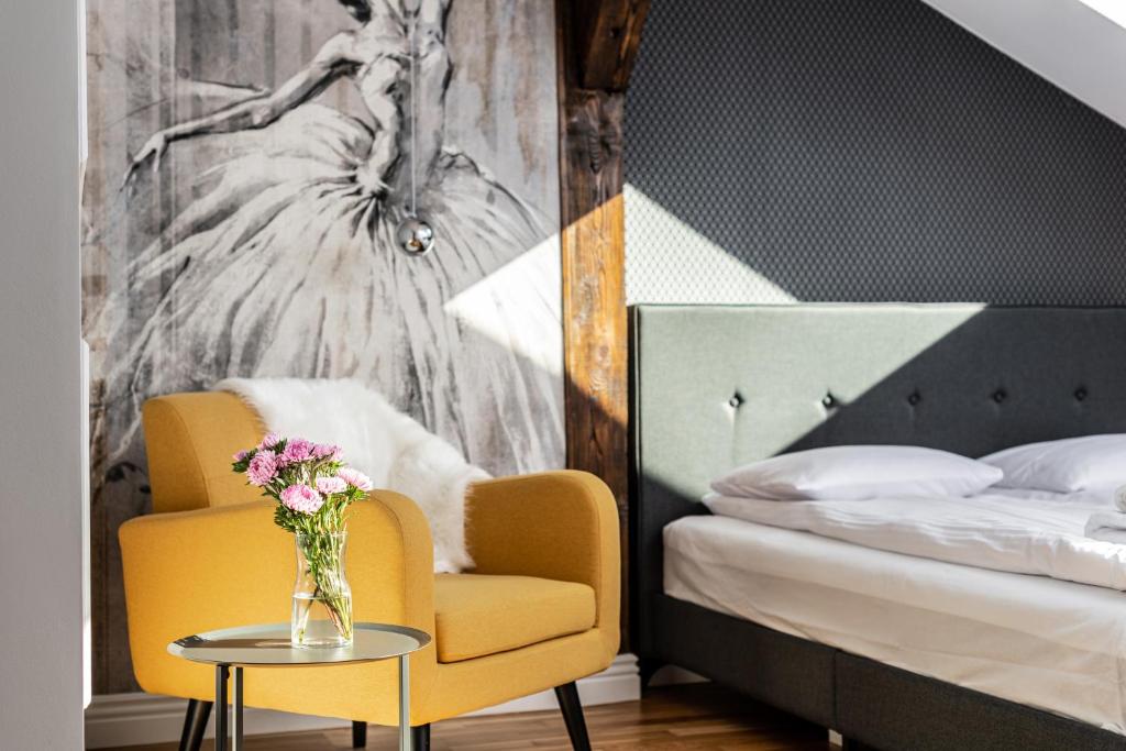 Un dormitorio con una silla amarilla y una mesa con un jarrón de flores en Riverside Premium Class Apartment en Cracovia