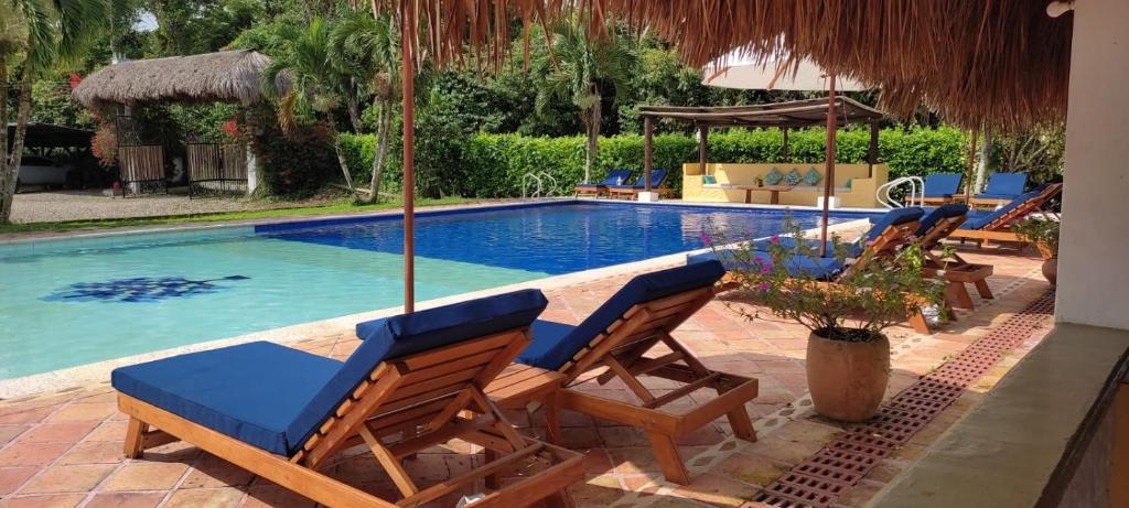 a swimming pool with two deck chairs and a swimming pool at Hotel Campestre Arboretto in Villavicencio